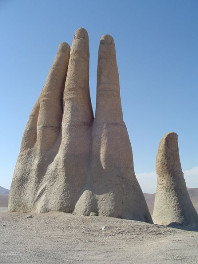 A sculpture of a giant hand reaches for the stars in the middle of the Atacama desert